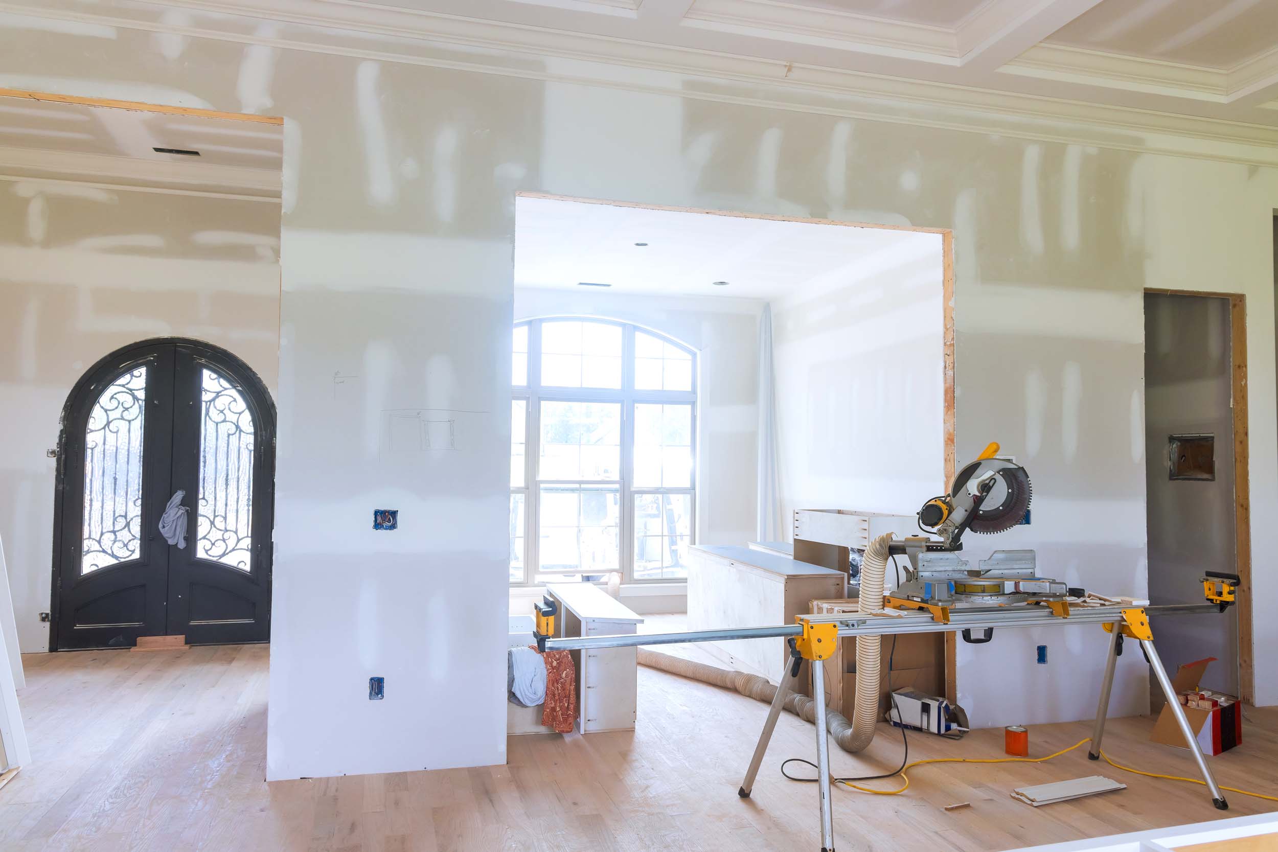 Construction progress showing partially finished interior with tools new doorway in home renovation project