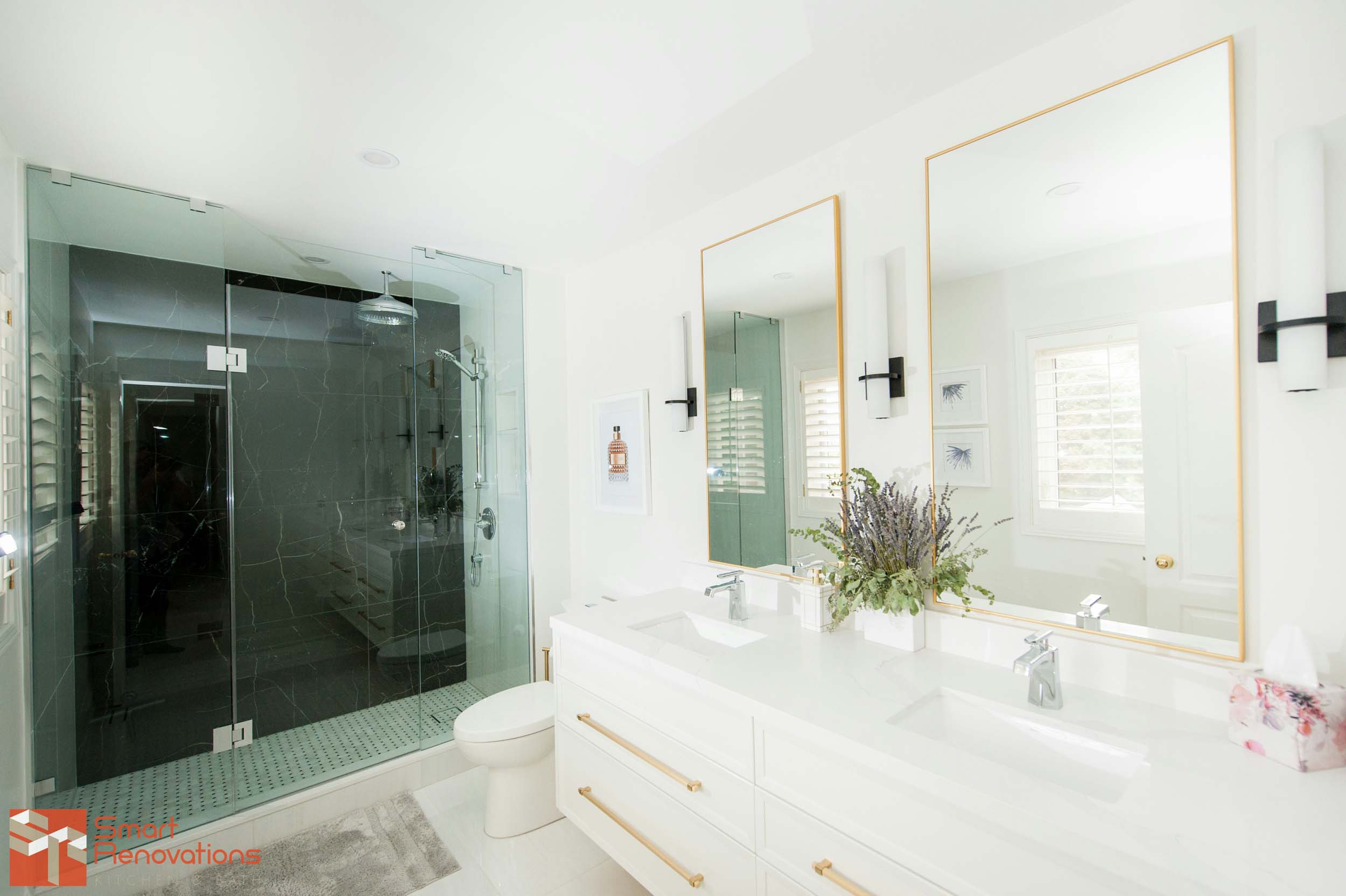Newly renovated bathroom with large mirrors and gold accents